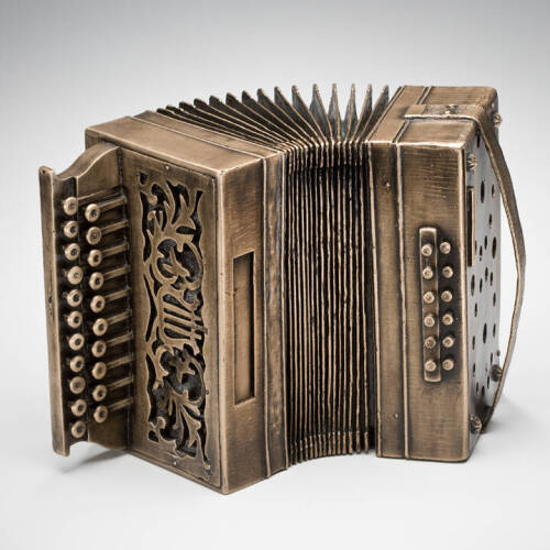 Small accordion made from bronze sitting on its side.